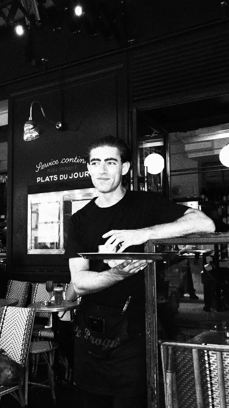 Un serveur devant l'ardoise des plats du jour